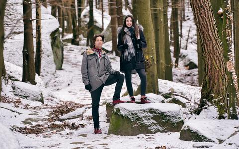 A man and woman stand in a winter landscape wearing barefoot boots.