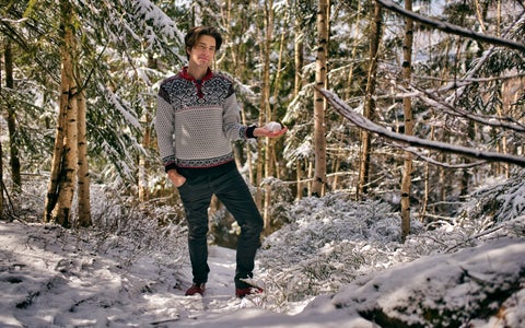A smiling man in barefoot shoes stands in a winter landscape.