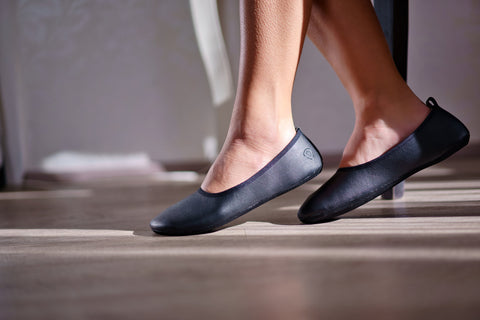 Feet in black barefoot ballet flats made from vegan leather.