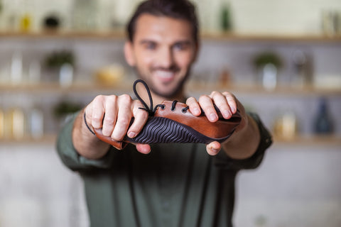 A man holding a barefoot shoe and twisting it