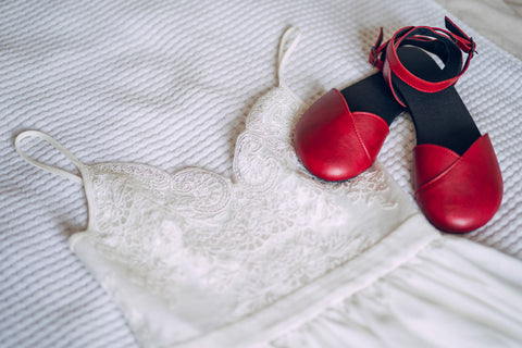 Ahinsa red barefoot sandals lying on a wedding dress 