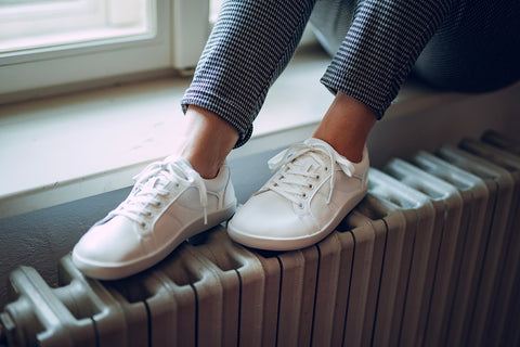 A woman sitting and wearing white barefoot sneakers by Ahinsa Shoes – Pura.