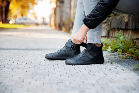 A woman fastening barefoot Ahinsa shoes with Velcro straps