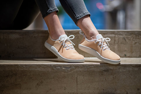 A woman in Ahinsa mesh sneakers sitting on steps