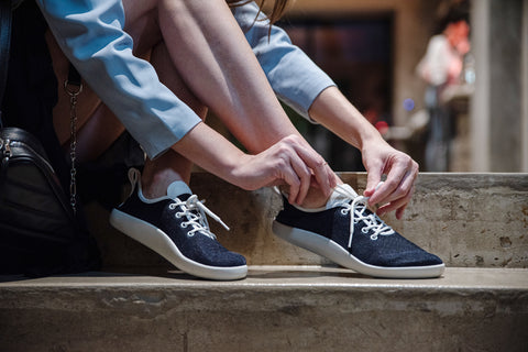 A woman lacing up her barefoot Ahinsa sneakers