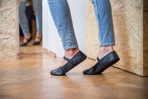 A woman in barefoot ballet flats standing on her tiptoes –  the shoe copies the position of the foot