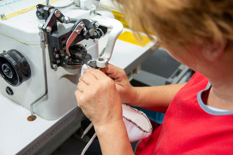 Unser Kollege in der Produktion näht das Obermaterial auf die Einlegesohle.