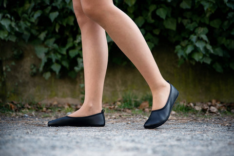 A woman walking down the sidewalk in Ahinsa barefoot ballet flats