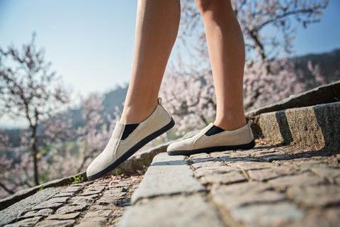 A woman walking up stairs in light-colored slip-on hemp sneakers without laces