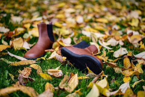 brown ankle-high boots lying on fallen leaves