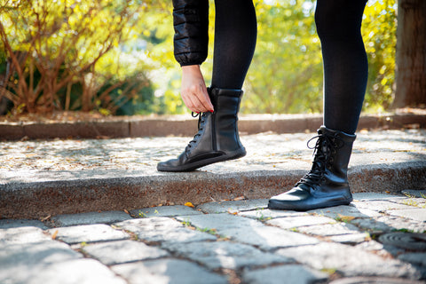 A woman lacing up Ahinsa barefoot boots