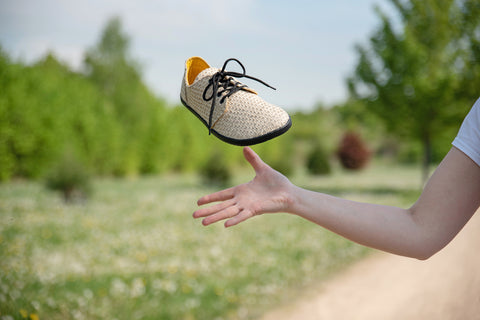 A woman throwing Ahinsa barefoot jute sneakers into the air. 