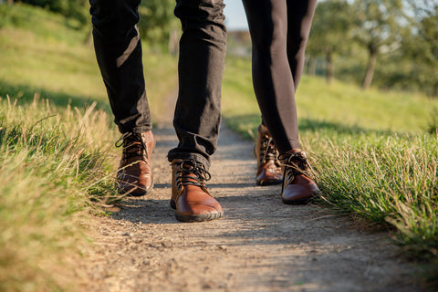 man and woman wearing ankle Ahinsa shoes are walking along a forest road