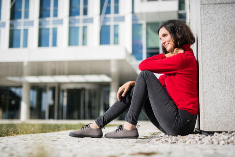 A woman sits on the ground wearing a pair of barefoot Ahinsa casual shoes.