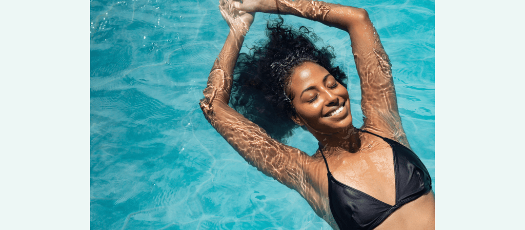 african american woman with afro hair floats in pool