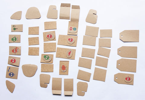 Forty three cardboard gift tags cut from an EcoSplat reusable water balloon box. They are small and different shapes.