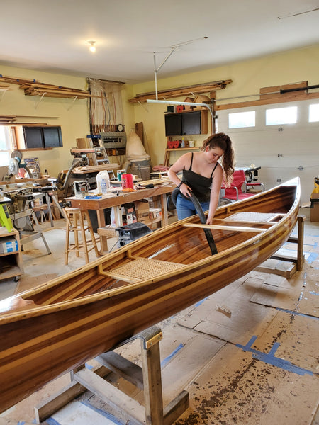 A young woman vacuums the inside of a canoe