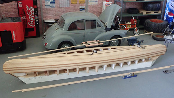 Overhead view of partially planked scale model canoe and model car