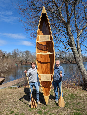 Alex Cutting and his father stand with the canoe they built together