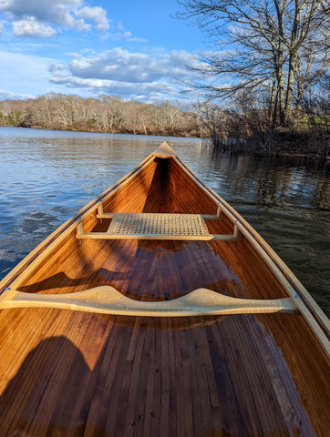 Photo taken from the stern of a wooden canoe on a lake