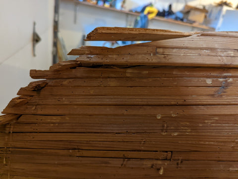 An incomplete woodstrip canoe in a workshop, in a state of disrepair