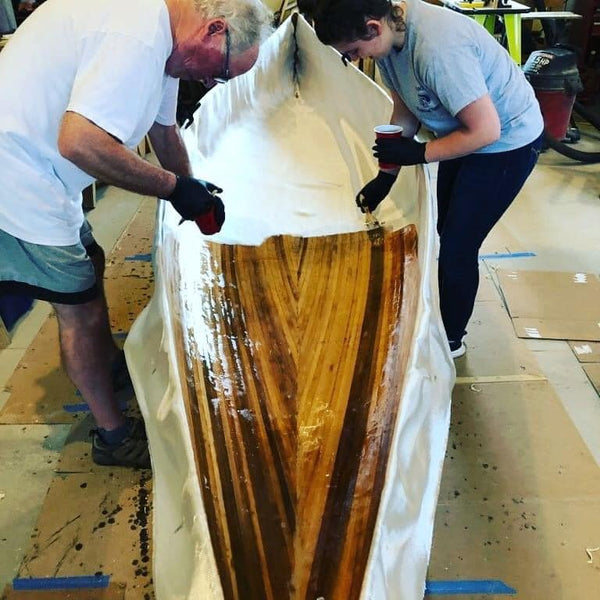 William John Beyette and granddaughter Zara apply epoxy to fibreglass the hull of a Bob's Special canoe