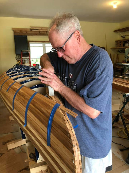 William John Beyette works with a chisel near the stems of a nearly-planked Bob's Special canoe