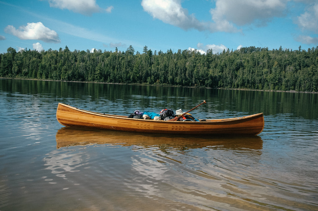 A wooden full of gear floats in a calm lake