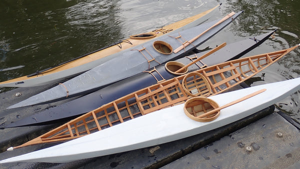 A collection of five scale model kayaks arrayed beside the water