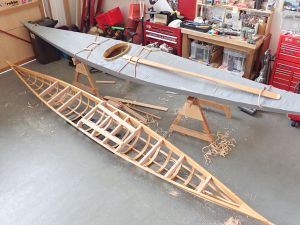 One finished and one partially complete Greenland kayak scale model, in a diorama workshop
