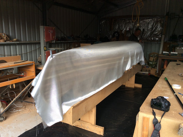 A Champlain wooden canoe draped with fibreglass in preparation for epoxy layup