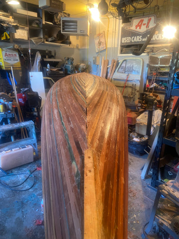 A fully planked but unfinished canoe hull in a workshop