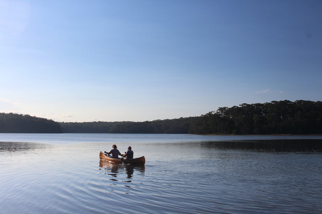 Keith and Nicki Endt paddle a Champlain wooden canoe across a calm lake