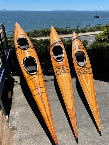 A trio of wooden kayaks propped up near a body of water