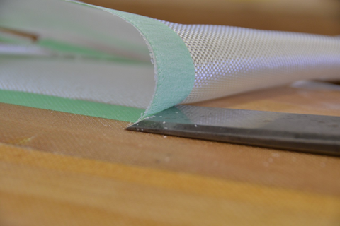 A sharp chisel sliding under the tape to trim the glass