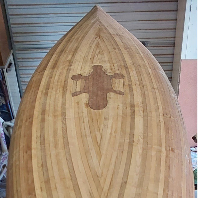 A partially finished wooden canoe with a platypus inlay