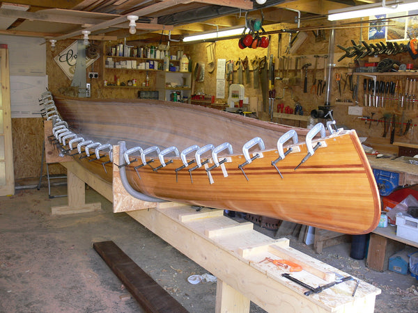 Wooden Prospector canoe under construction with clamps all down the inner gunwale