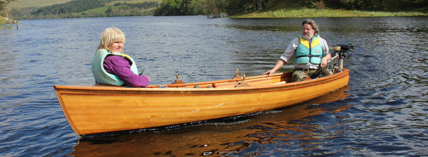 Jon Belton sits in the stern of skiff with a woman in the bow