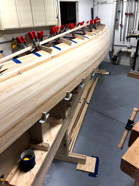 A partially completed Nomad 17 canoe sits in a workshop with clamps in place to allow stapleless building