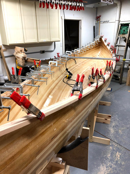 A partially completed Nomad 17 with clamps all along its length holding the gunwales on