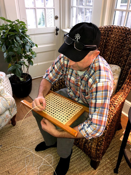 Ty Bailey sits in a chair caning a canoe seat