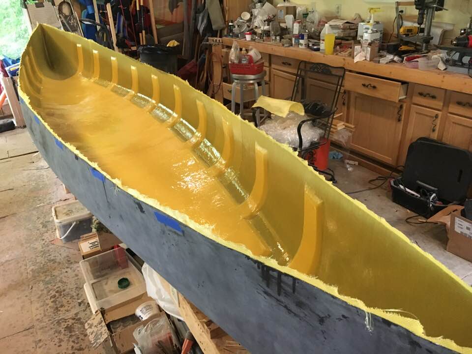 Molds and tension straps removed from open hull of composite canoe, now ready for trim