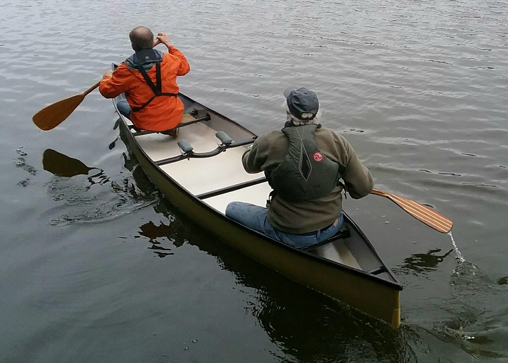 Randy Pfeifer and a paddling partner, seen from behind, test his composite canoe on the water