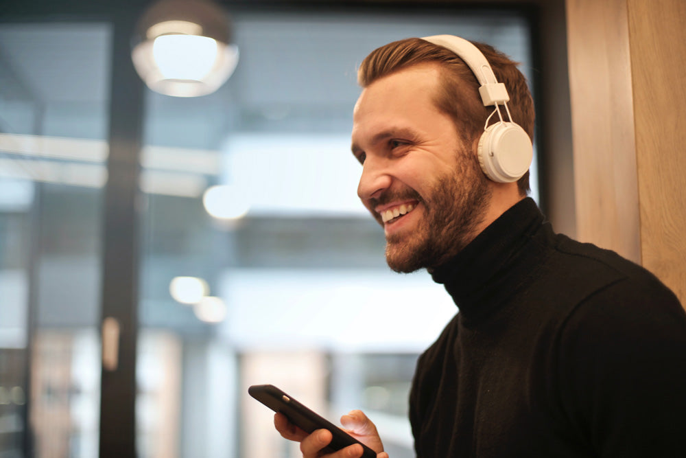  man wearing white headphones and holding phone