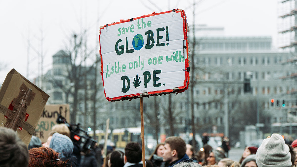 Menschen demonstrieren in Berlin für das Klima mit einem Schild auf dem “Save the Globe it's the only one with Dope” steht.