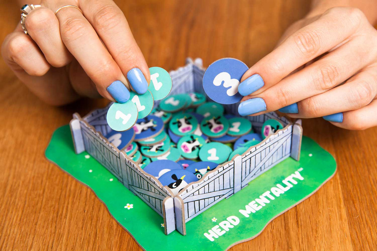 A person putting cow tokens in a Herd Mentality cow paddock