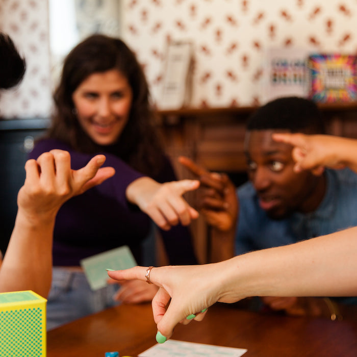 People pointing fingers at one another while playing The Chameleon game.