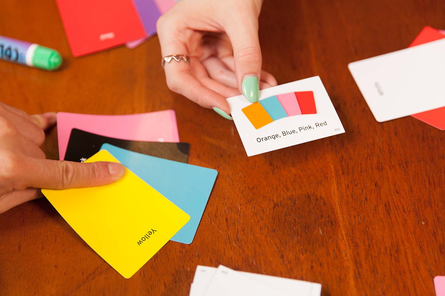A person laying down an options card, while another lays down several colour cards
