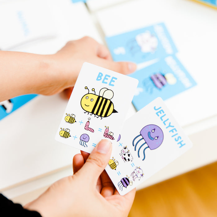 A person holding 2 animal cards, while playing a game of Muddles.