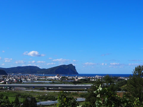 青空とシリパ岬、余市の町の写真